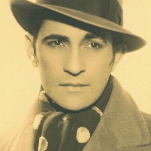 Portrait of Con Colleano in hat and coat looking away from camera