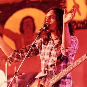 Musician with guitar singing into a microphone.