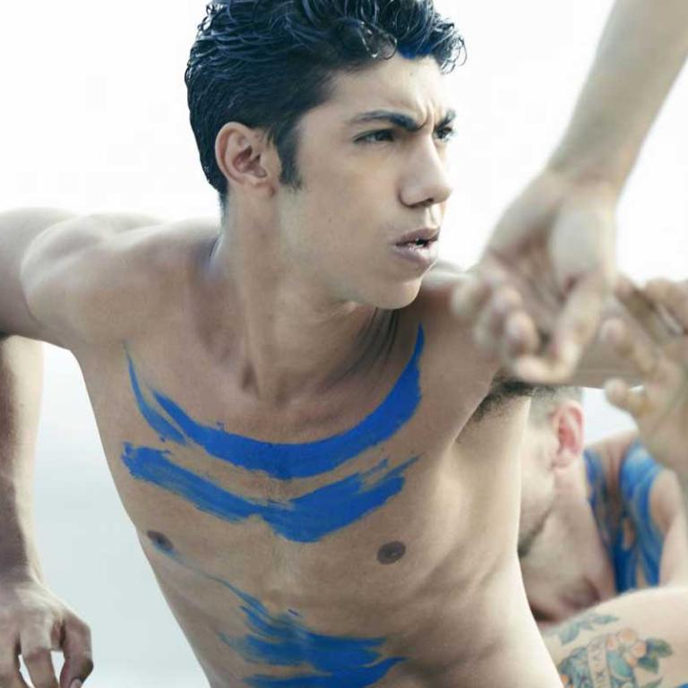 Two young Indigenous male dancers wearing body paint and performing a traditional dance.