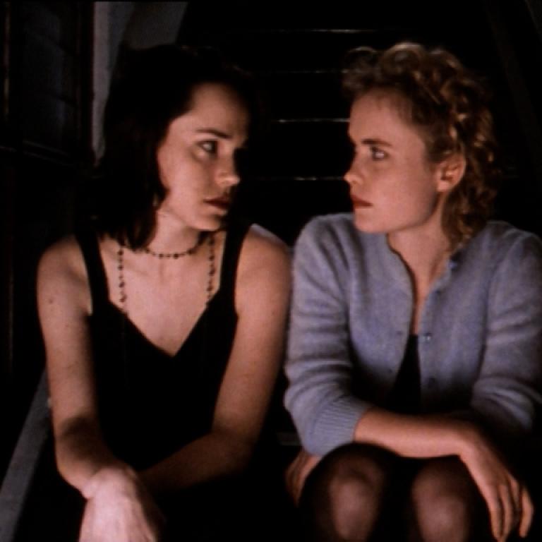 Frances O'Connor sitting next to Radha Mitchell by a lit candle. They are staring intently into each other's eyes