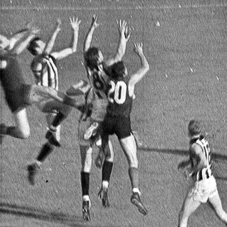 Australian Rules Football players jumping for the ball in the 1964 grand final match.