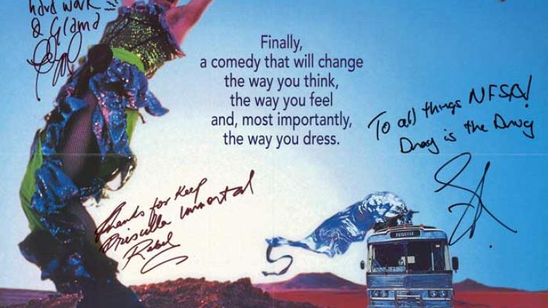 Australian poster: The Adventures of Priscilla, Queen of the Desert Hugo Weaving with arms in the air, wearing green and blue sequined outfit, holding green scarf. Silver bus with a silver draped figure on the roof is in the background to the right. Header text list of main cast members in white block print.
