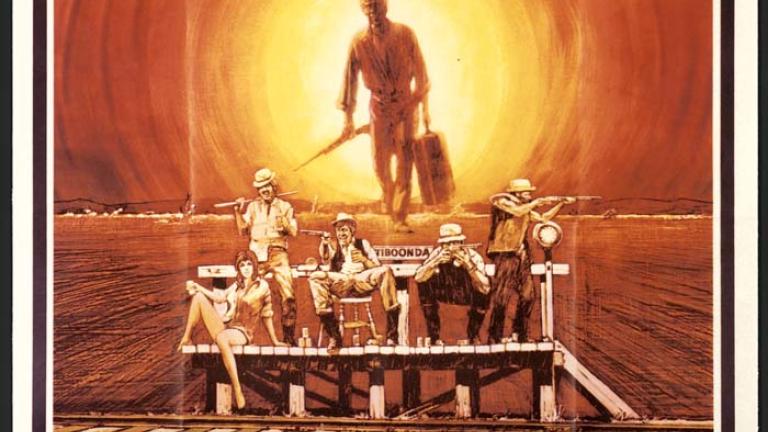 Orange tones, 4 males and a female waiting at a station, holding beer cans and guns. A male carrying a suitcase and gun behind. Header: 'Outback. Have a drink, mate? Have a fight, mate? Have a taste of dust and sweat, mate? There's nothing else out here.