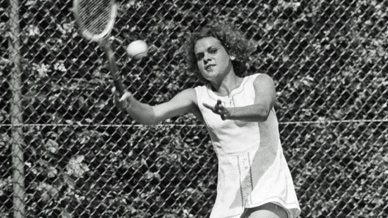 Evonne Goolagong-Cawley holding a wooden tennis racket and about to hit a tennis ball.