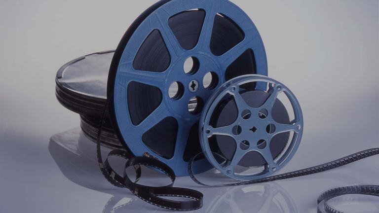 Two film canisters sit on a table service with the film partially unwound.