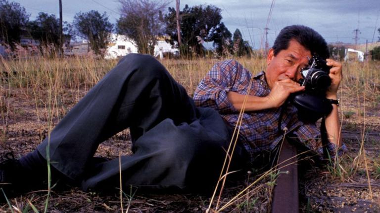 A man lying on his side on the ground taking a photograph