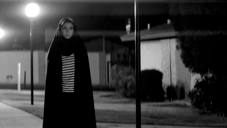 A teenage girl walking alone through a quiet street at night.