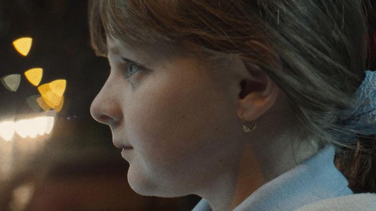 Close up of a young girl's face in profile. She has her hair tied back and is looking straight ahead intently.