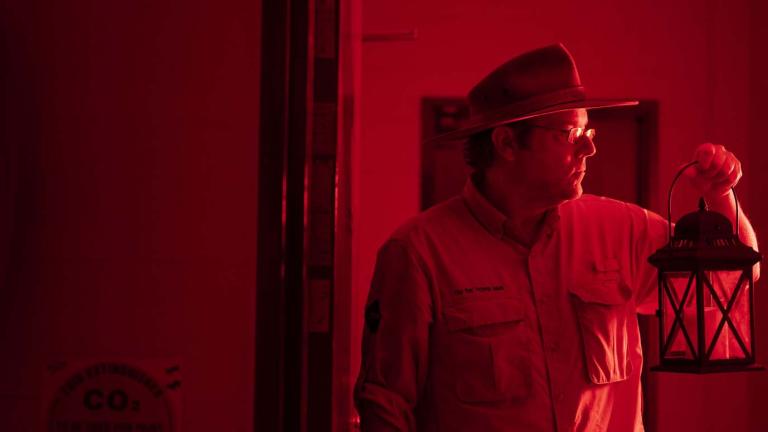 Tim the Yowie Man holding a lantern backstage during the NFSA Ghost Tour