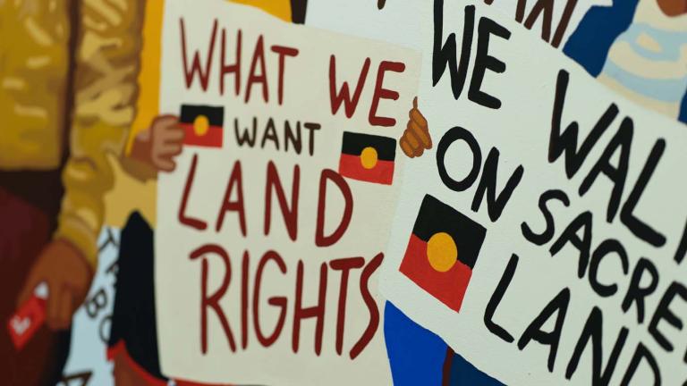 Protesters hold banners calling for Aboriginal land rights at a march