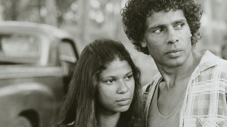 A young Aboriginal woman and man looking at something off camera, with serious-looking expressions.