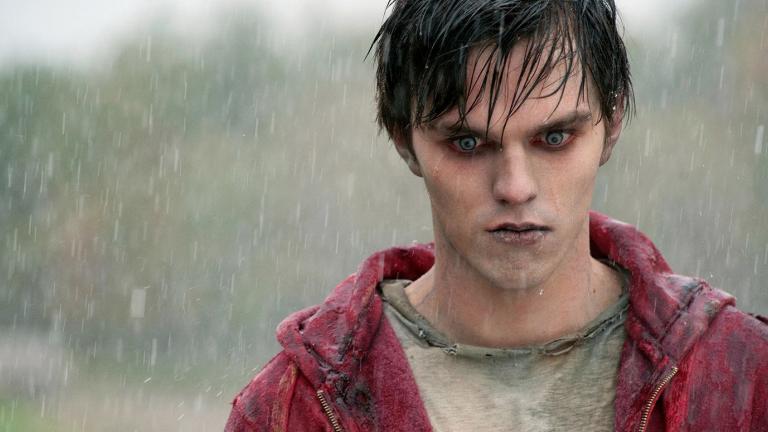 Head and shoulders shot of a young man standing in the rain. He has the look of a zombie - his skin has a grey/bluish tinge and his eyes are red..