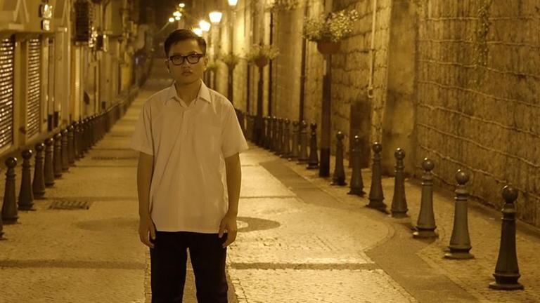 A man standing alone on an empty street at night time.