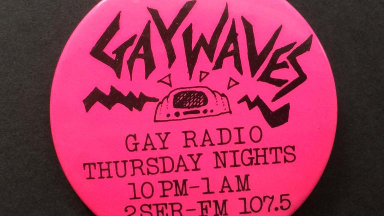 Hot pink coloured round badge with the word Gaywaves printed on it.