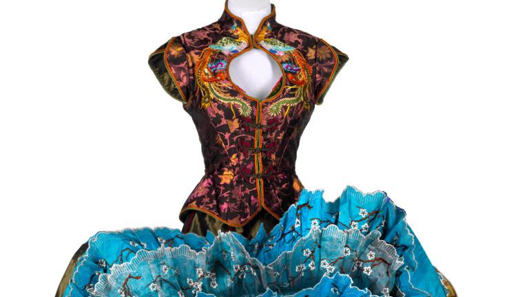 Costume on a mannequin featuring a bodice with an ornate asian-influenced design and a full skirt that has been turned up to show the layers of lace petticoats under the main fabric. The costume was worn by a dancer in the film Moulin Rouge!