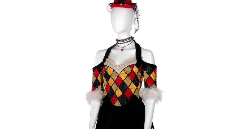 Costume on a mannequin featuring off-the-shoulder sleeves and a bodice and a full skirt that has a harlequin design on it. The costume was worn by a dancer in the film Moulin Rouge!