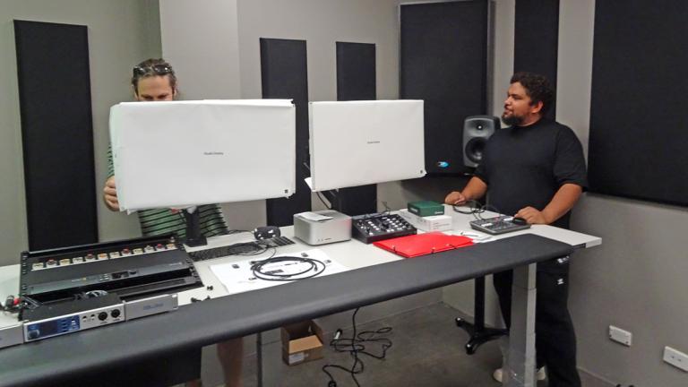 Inside the video services department at the NFSA two men are standing behind and beside some white screens