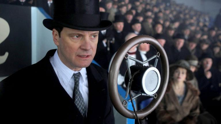 Actor Colin Firth wearing a suit, tie and hat and speaking into a 1930s style microphone in a scene from the film The King's Speech. 