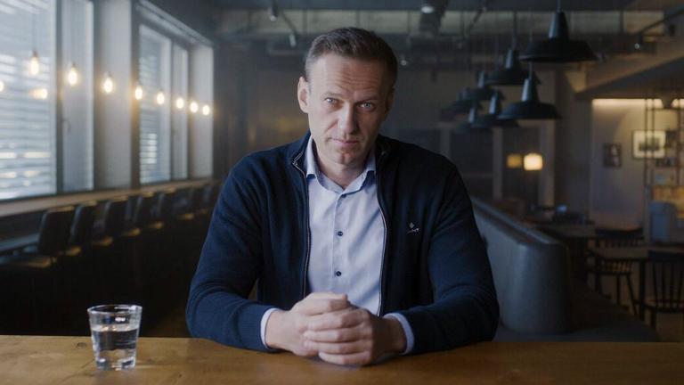 Russian politician Alexei Navalny seated at a table and looking directly at the camera.