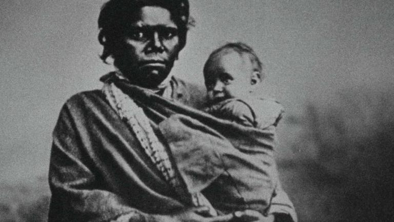 A black-and-white photo dating from the early 20th century of an Indigenous woman holding a baby.