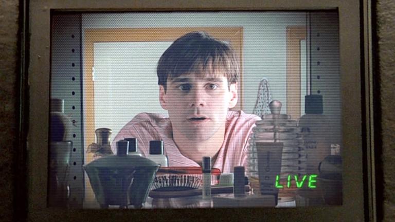 A man who appears to be in a kitchen staring blankly through a glass panel. The word 'LIVE' is written on the bottom right of the screen.