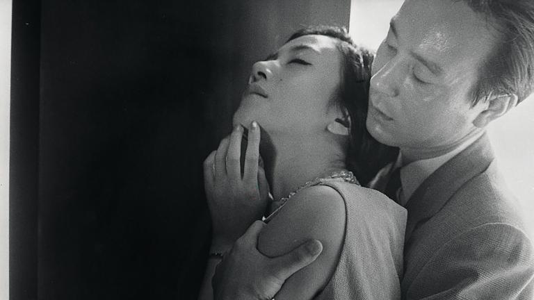 A woman standing with her back to a man who has his arms around her and is holding her tightly.