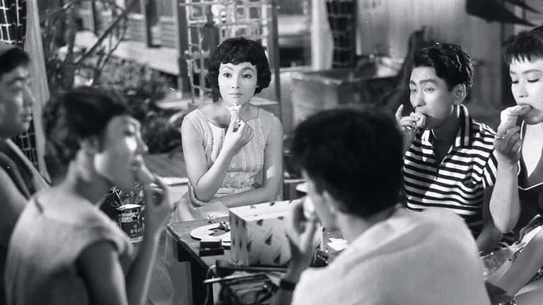 A group of Japanese people sitting around a table eating ice cream cones