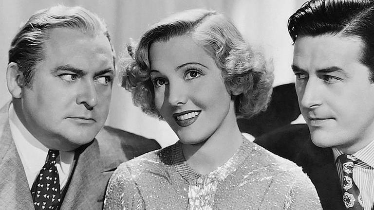 Head and shoulders shot of 3 people pictured side by side. In the centre is a young woman smiling, on the left is a stern-looking middle aged man who is looking at her and on the right is a younger man looking at her. The image is a still from a 1930s film, Easy Living.