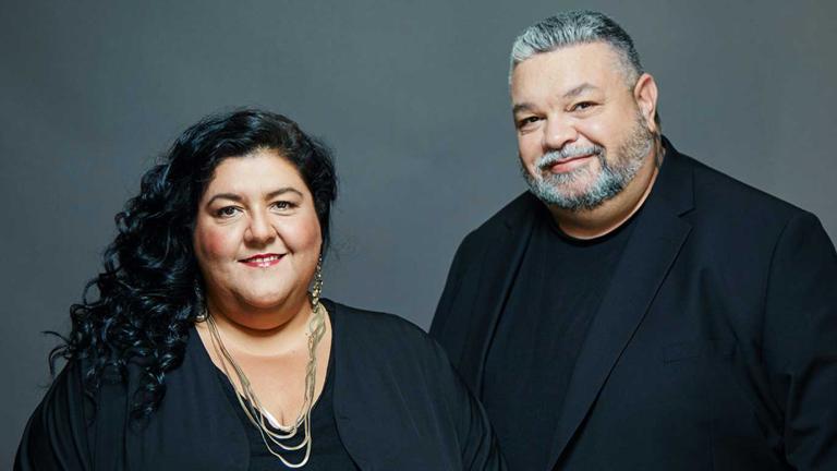 Head and shoulders image of Indigenous filmmakers Gillian Moody and Adrian Russell, both dressed in black and smiling at the camera.