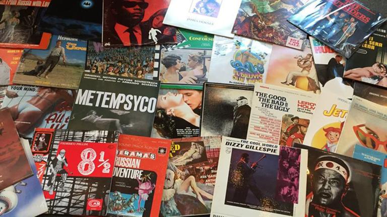 A lot of vinyl record covers spread out on a table all overlapping each other.