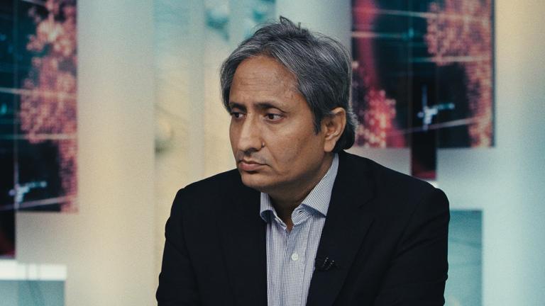 An Indian man wearing a suit, seated and looking very forlorn.