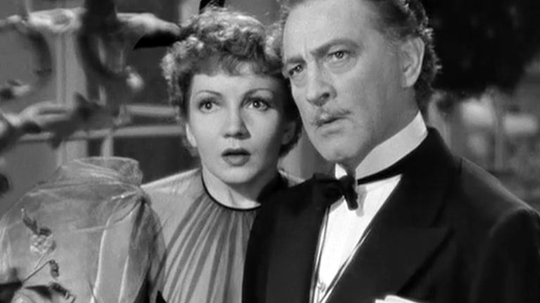 Head and shoulders shot of actors Claudette Colbert and John Barrymore in formal attire, they are both looking straight ahead and seem to be surprised at something. From a 1929 film Midnight.