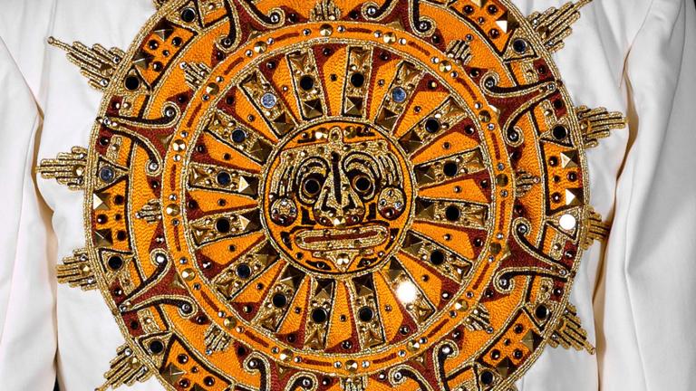 Detail of elaborate sun-shaped Aztec sundial design on the back of a white Elvis Presley jumpsuit made for the film ELVIS