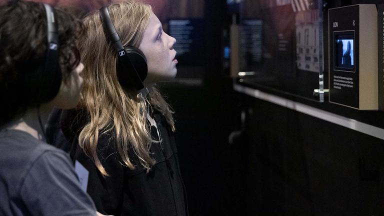 A young girl wearing headphones is looking at a screen in a gallery space at the NFSA