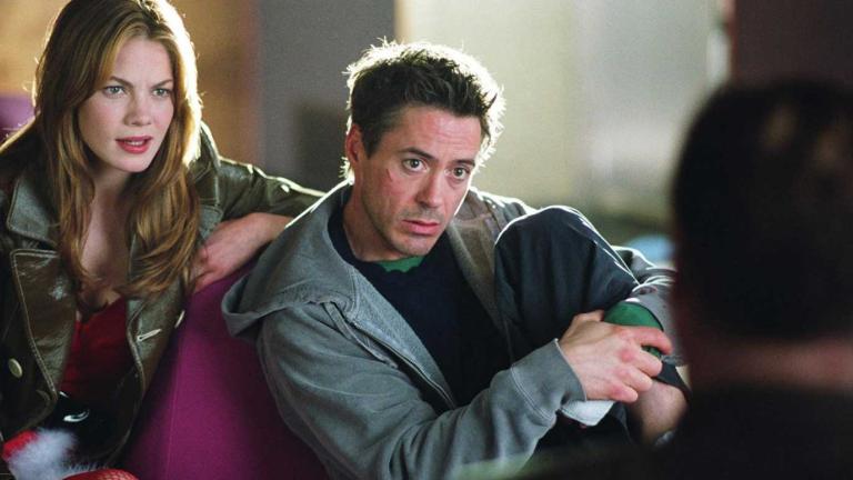A young woman and a man seated, looking at something off camera.