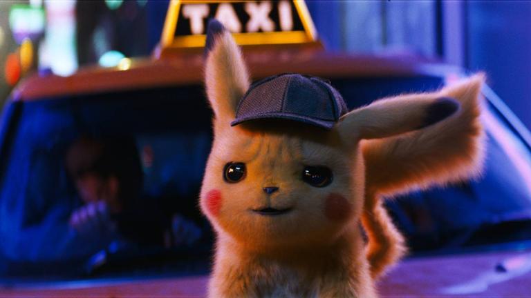 The small furry-blonde video game character Pikachu with rosy cheeks and wearing a Sherlock Holmes detective cap sitting on the bonnet of a taxi
