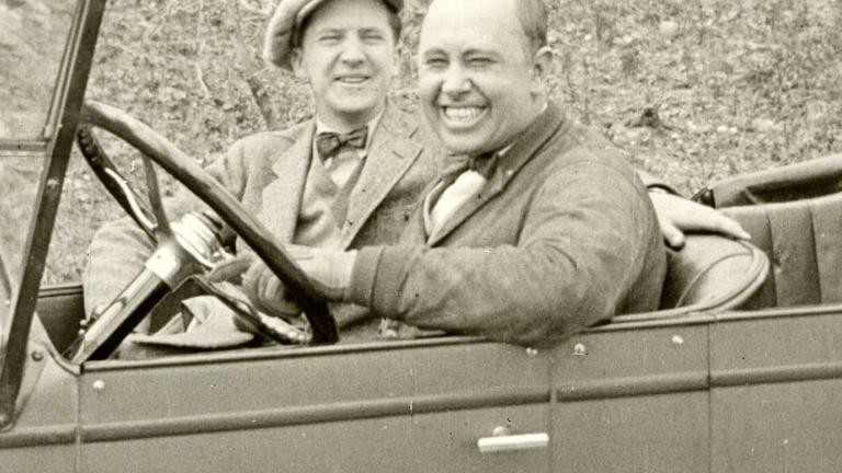 Two men sitting in a motor car and smiling at the camera, c1924.