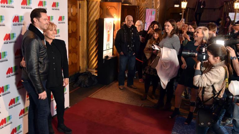 Actors Hugh Jackman and Debora-Lee Furness at a film premiere being photographed by media.