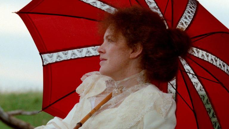 A woman sitting under a red umbrella