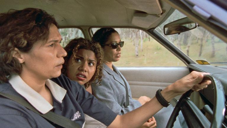 Three women sitting in a car pictured from side on.