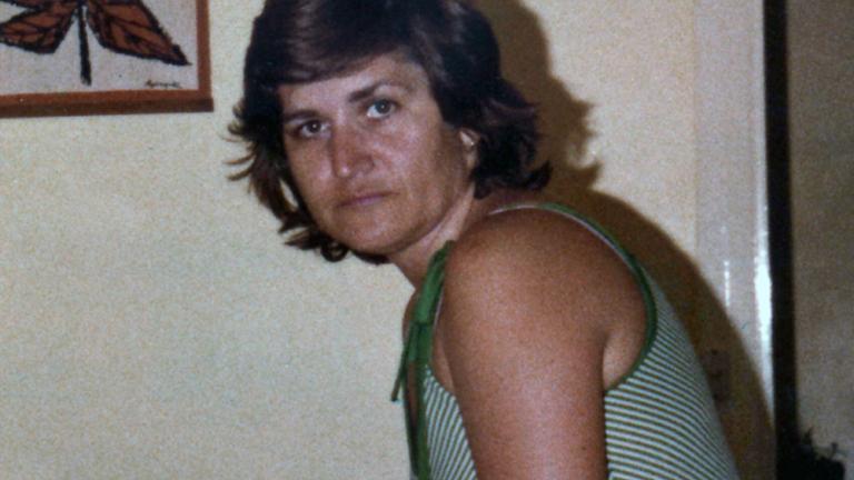 Upper body shot of a woman standing side on and looking sideways towards the camera