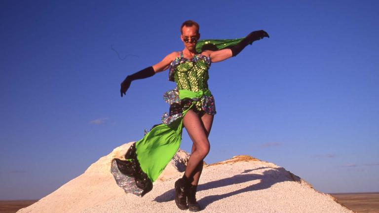 Hugo Weaving in a green dress standing on a desert rock while filming The Adventures of Priscilla, Queen of the Desert