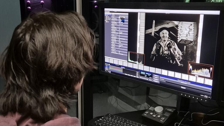 A staff member at the National Film and Sound Archive examines an image from a black-and-white film on a computer monitor.