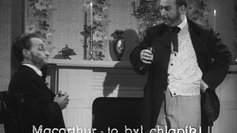 Two gentlemen in 19th century attire standing in front of a fireplace holding drinks
