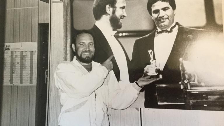 Producer Harvey Shore standing in front of a blown up image of himself with Simon Townsend holding a Logie Award.