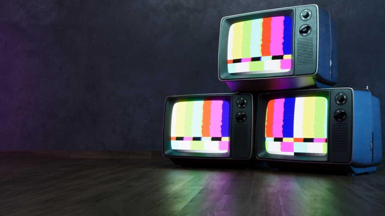 A stack of 3 televisions sets with a colour test pattern on the screens, on a dark background.