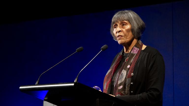 Aunty Violet Sheridan speaking on a podium