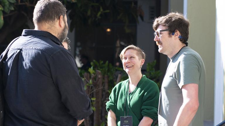 A group of three chatting in a courtyard