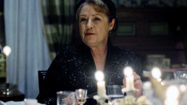 Actor Noni Hazelhurst dressed in black and seated at a dinner table in a scene from the show A Place to Call Home