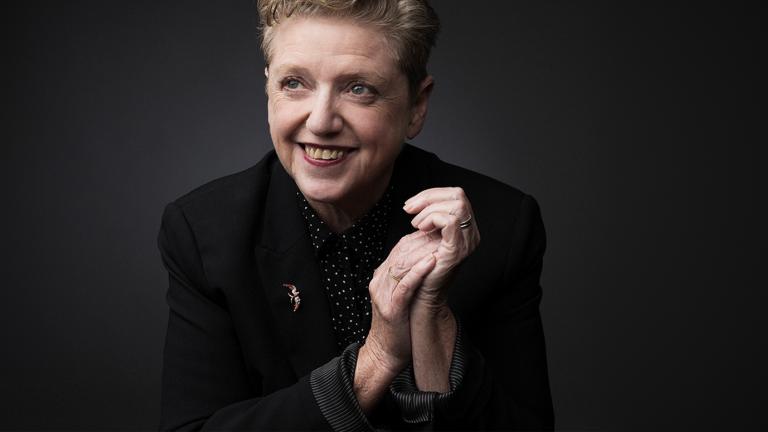 Robyn Archer smiling with her hands clasped in front of her